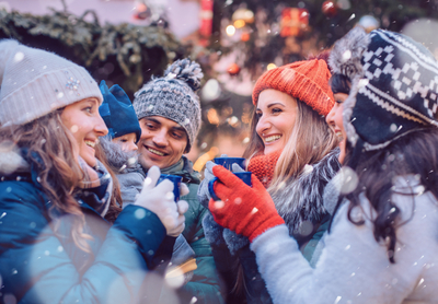 Group of friends drinking mulled wine in the cold on a Christmas Market with fun and laughter