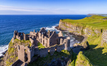 Ruins of medieval Dunluce Castle, cliffs, bays and peninsulas. Northern coast of County Antrim, Northern Ireland, UK.  Aerial view.