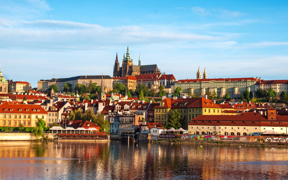 Panorama von Prag mit Blick auf die Moldau und die Prager Burg bei sonnigem Wetter.