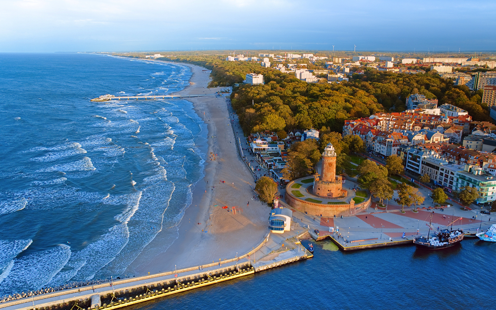 Luftaufnahme einer Küstenstadt mit Strand, Meer und Leuchtturm.