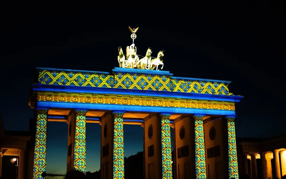 Das Brandenburger Tor bei Nacht mit bunter Lichtprojektion.