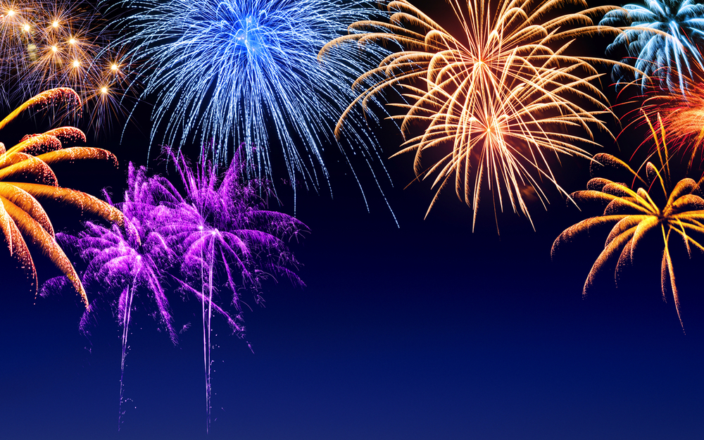 Verschiedene bunte Feuerwerkskörper vor einem Nachthimmel.