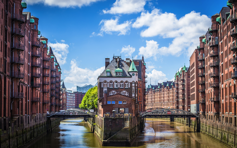 Historische Speicherstadt in Hamburg mit Wasserkanal und Brücken bei blauem Himmel.