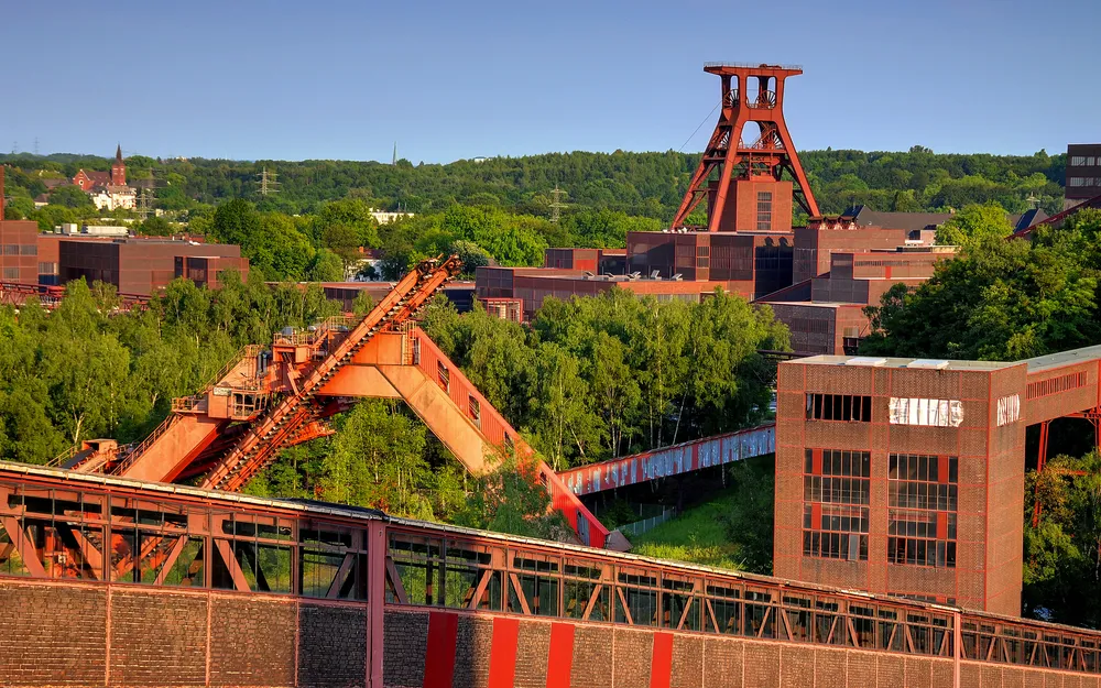 Industriekultur mit Förderturm und grüner Umgebung bei Sonnenschein.