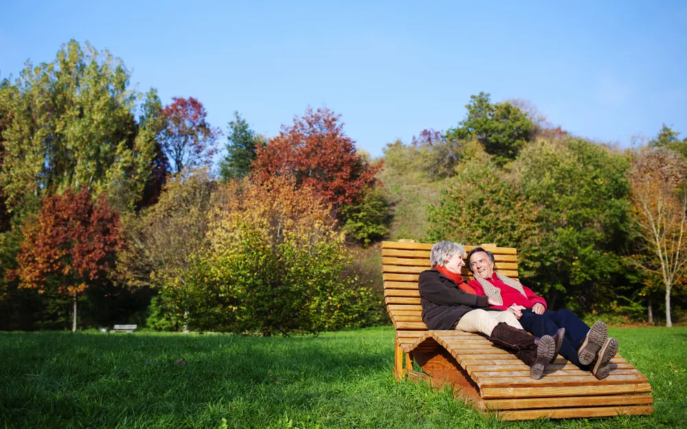 Älteres Paar entspannt auf einer Bank im herbstlichen Park.