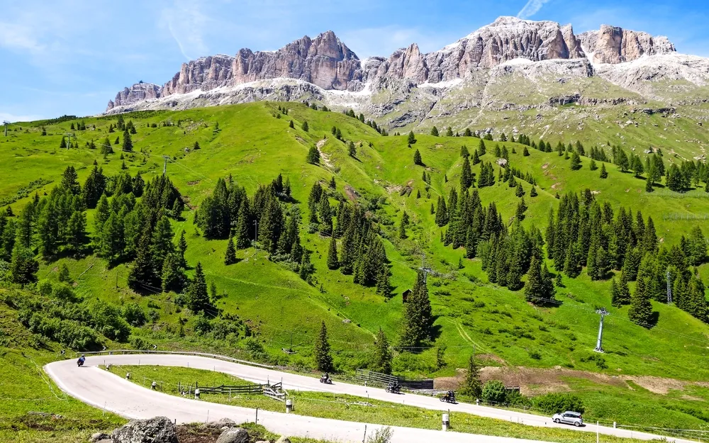 Berglandschaft mit grünen Hügeln und einer Straße im Vordergrund.