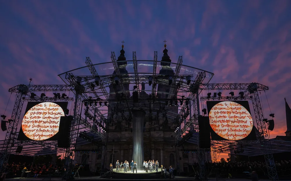 Open-Air-Bühne bei Sonnenuntergang mit inszenierter Aufführung und Lichtprojektionen.