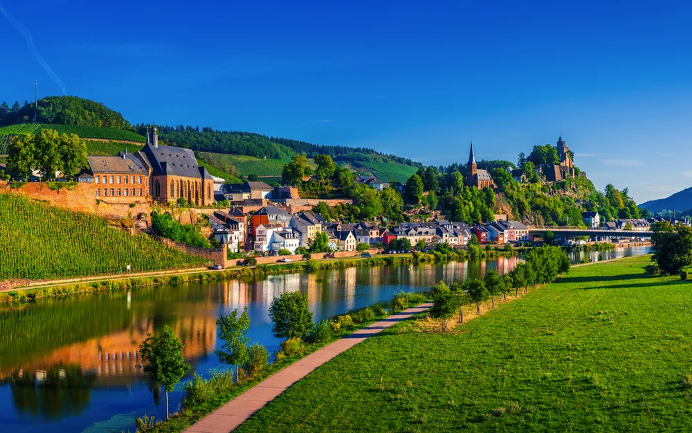 Stadtlandschaft mit Fluss, Hügeln und historischer Architektur im Sonnenschein.