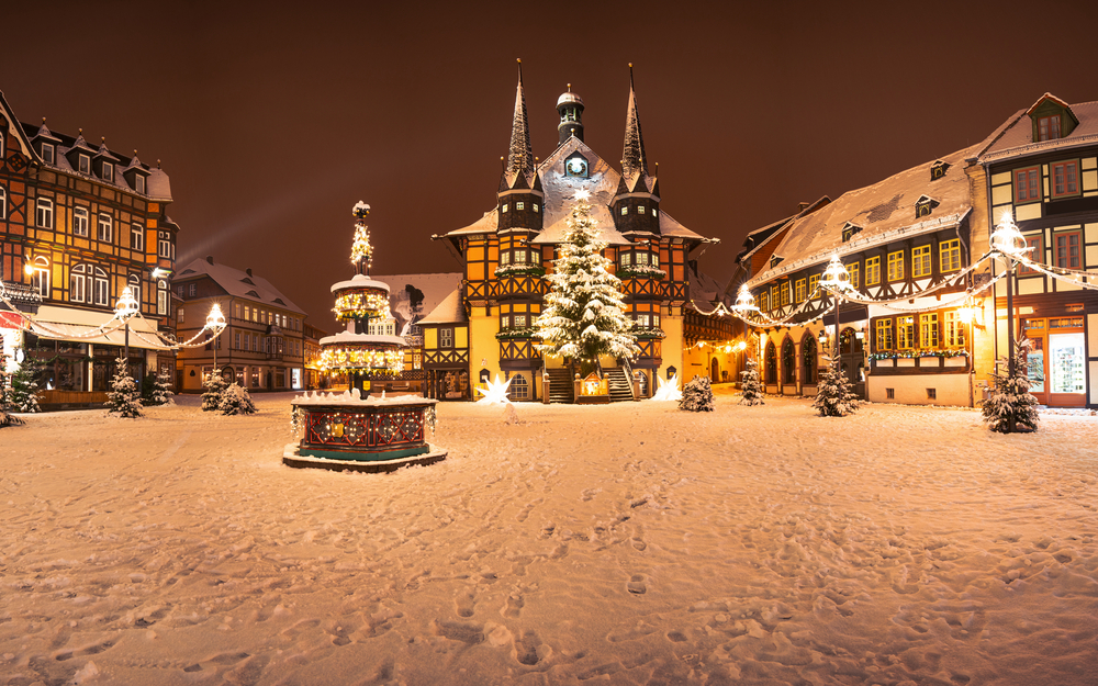 Verschneiter Marktplatz mit beleuchteten Fachwerkhäusern und Weihnachtsbaum.