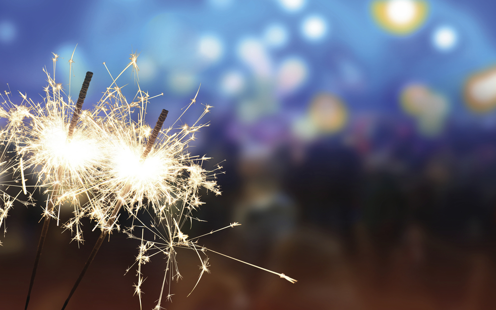 Wunderkerze vor blauem Hintergrund als Motiv für „Silvester ins Blaue“.