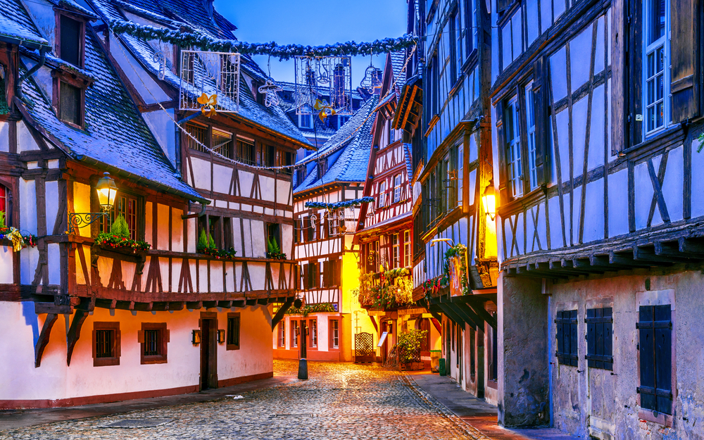 Fachwerkhäuser in einer malerischen, mit Kopfsteinpflaster gepflasterten Altstadtstraße bei Dämmerung.
