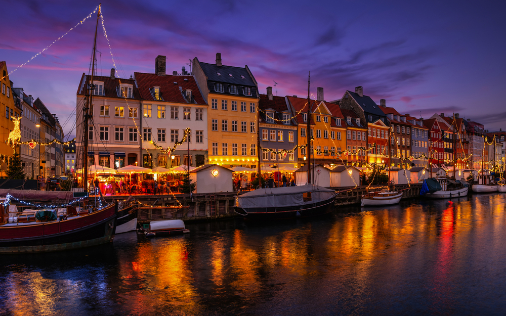 Abendstimmung mit beleuchteten Häusern und Booten an einem Kanal.