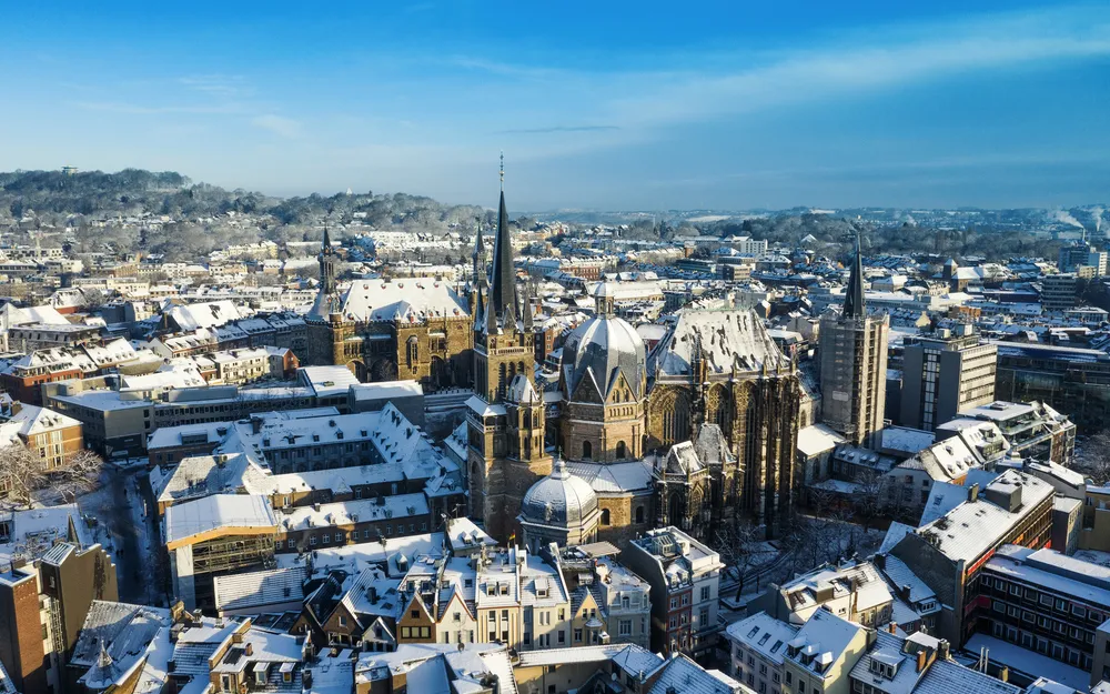 Luftaufnahme von Aachen im Winter mit schneebedeckten Dächern und dem Aachener Dom im Zentrum.