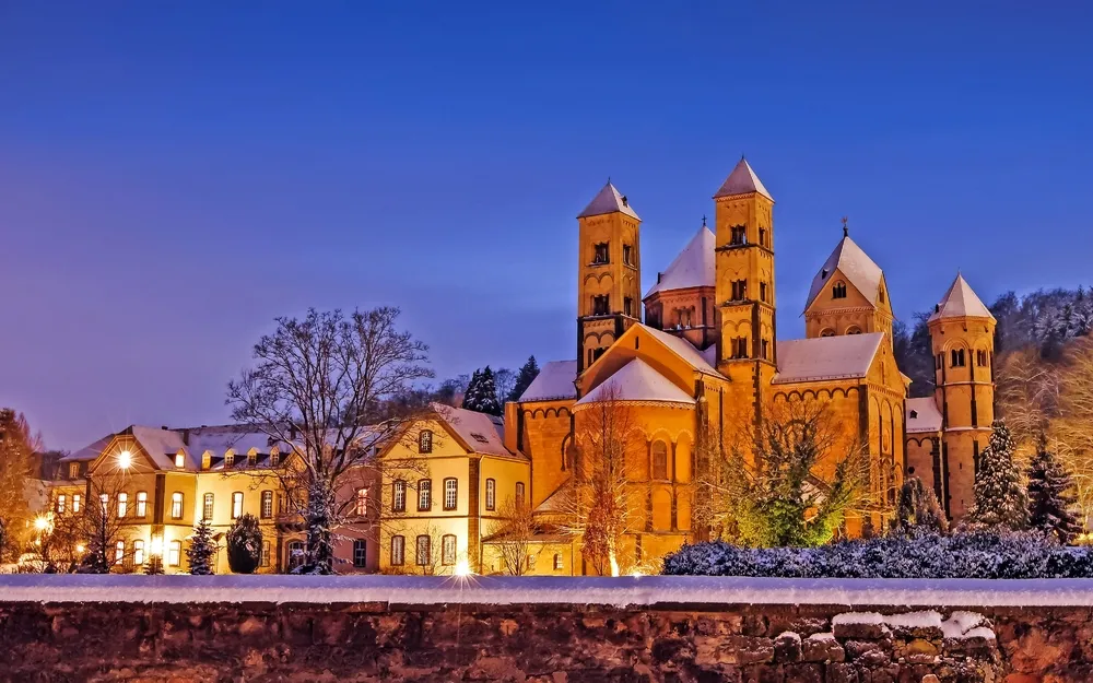 Abtei Maria Laach im Winter bei Abenddämmerung beleuchtet.