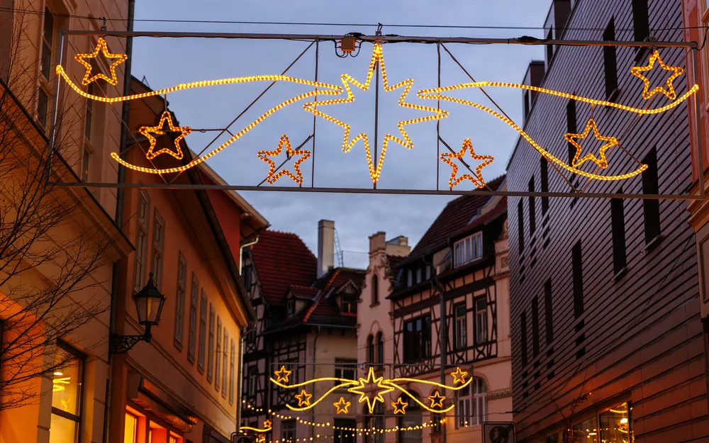 Straße mit weihnachtlicher Beleuchtung und Fachwerkhäusern bei Dämmerung.