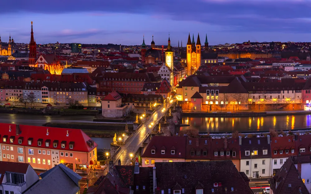 Abendliche Panoramaansicht von Würzburg mit erleuchteten Gebäuden und Fluss.