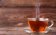 Tasse Tee mit Dampf auf braunem Holztisch